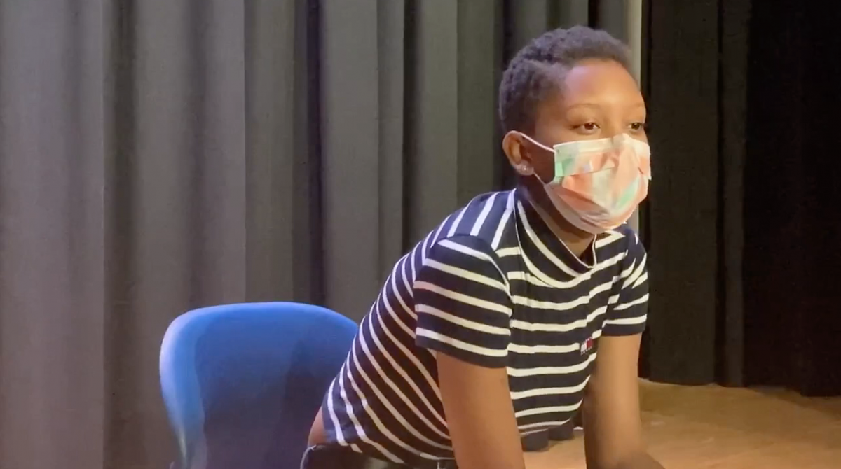 Person wearing a mask and sitting in a chair, leaning forward