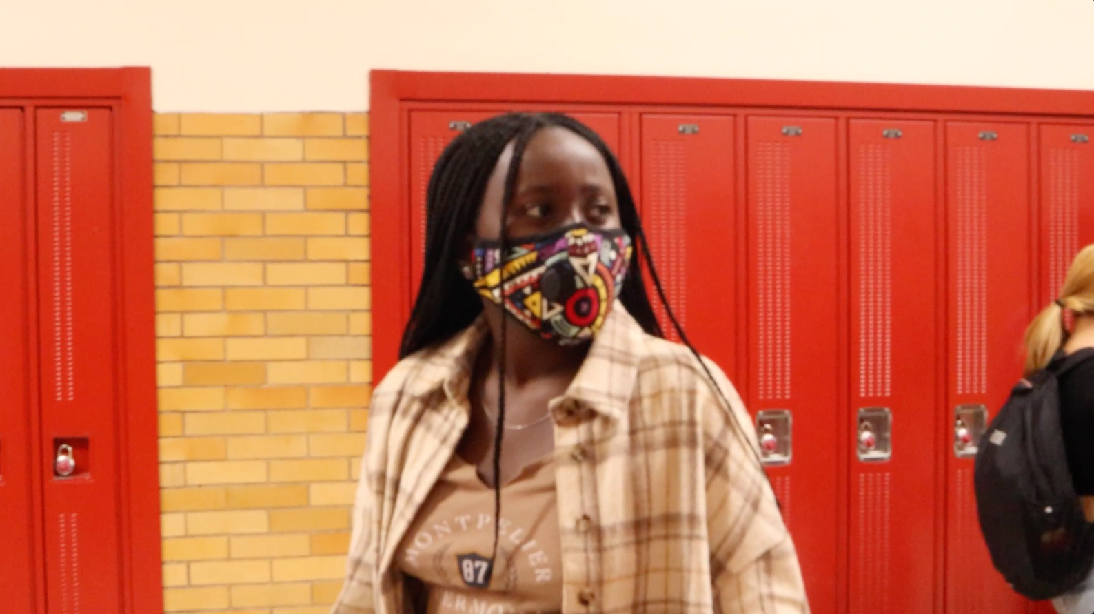 Person standing in front of lockers wearing a mask