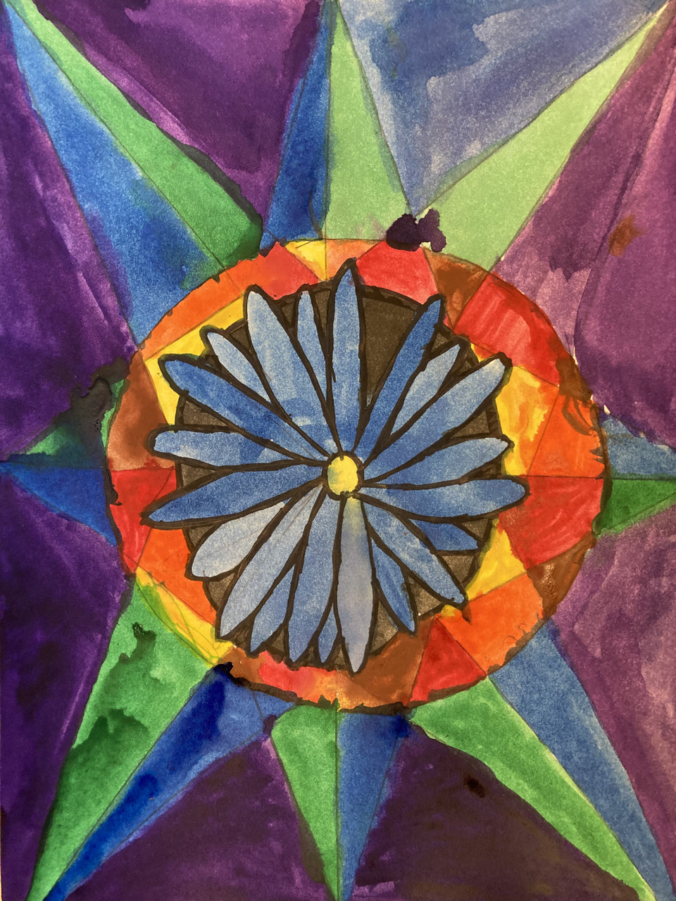 A blue flower in the center of an orange, yellow and red circle with blue, green and purple background