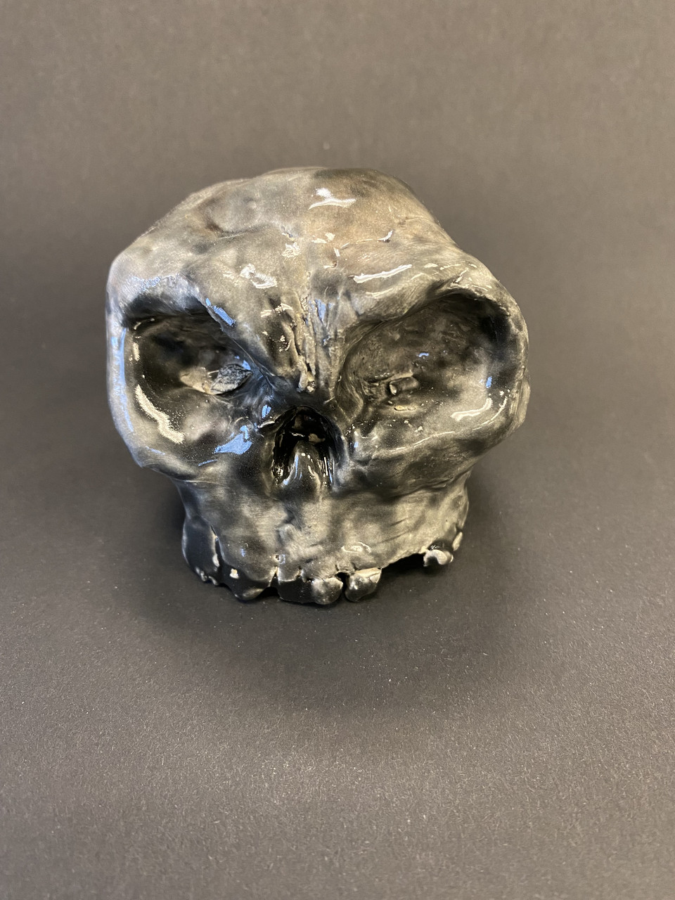 Sculpture of skull on gray background.