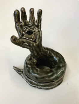 Ceramic hand coming out the hole made by a coiled serpent