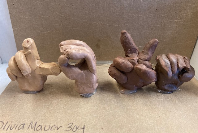 clay sculpture of hands showing sign language
