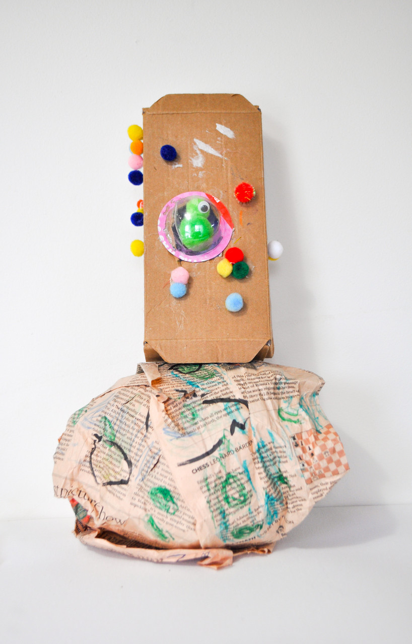 A sculpture of a cylinder on top of planet earth with pom poms.