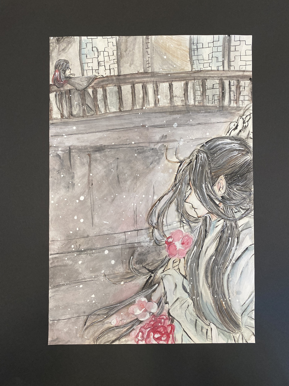 Woman on snowy day next to bridge smelling pink flower.