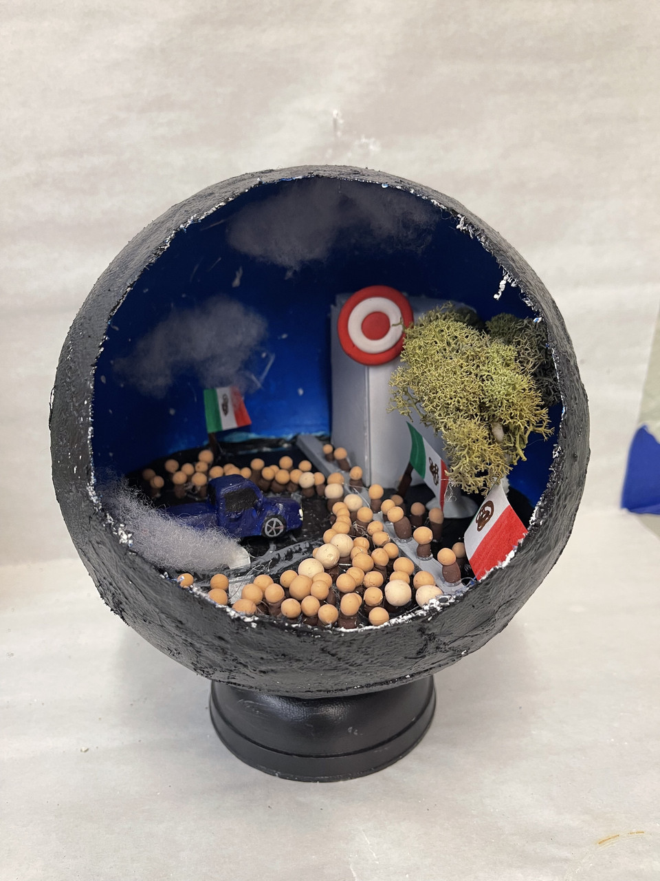 Scene of a place in an open ball like a terrarium. Tiny Mexican flags are in the scene
