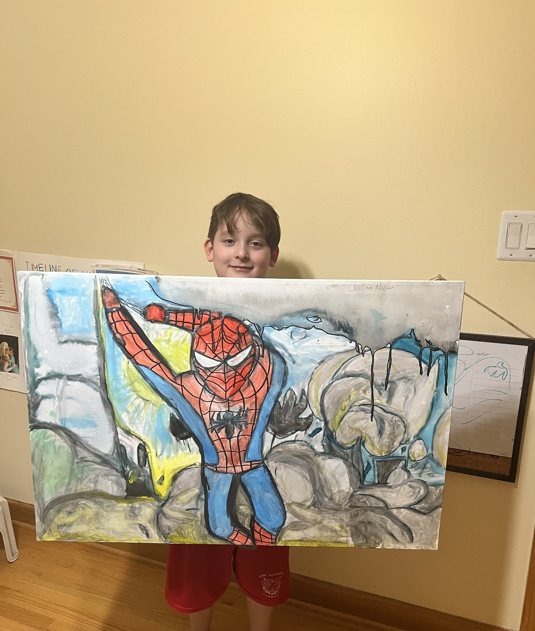 Image of a child holding a Spiderman painting