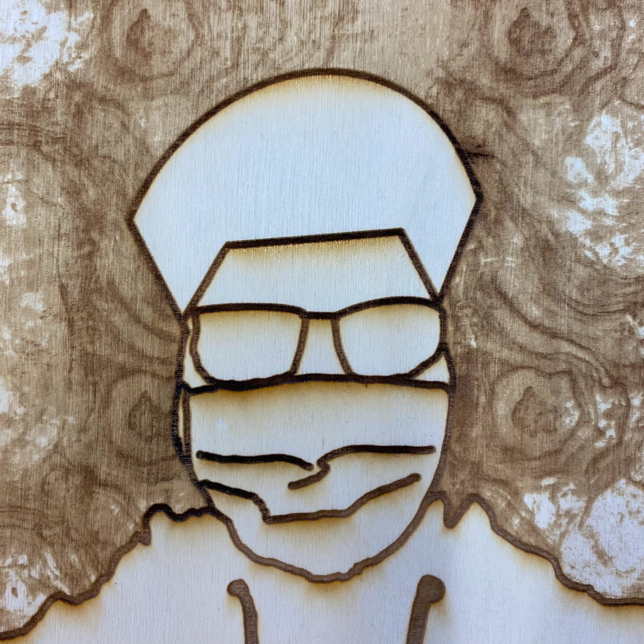 Laser engraved drawing of a person with a face mask on wood