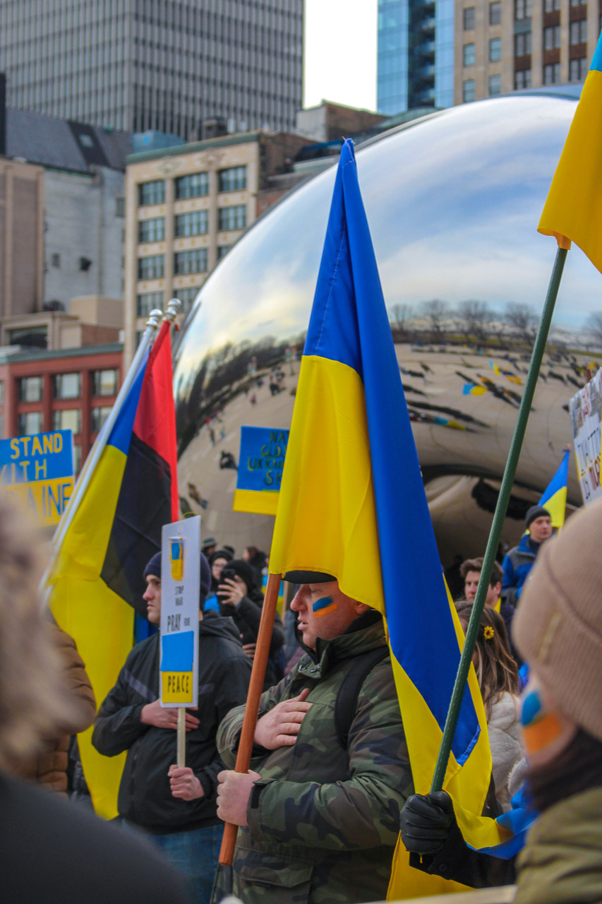 People holding Ukrainian flags in front of "Cloud Gate"