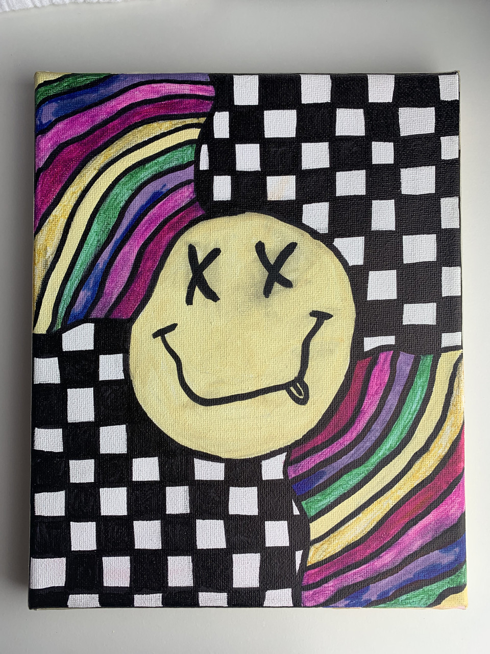 A smiley face with rainbows and a checker pattern
