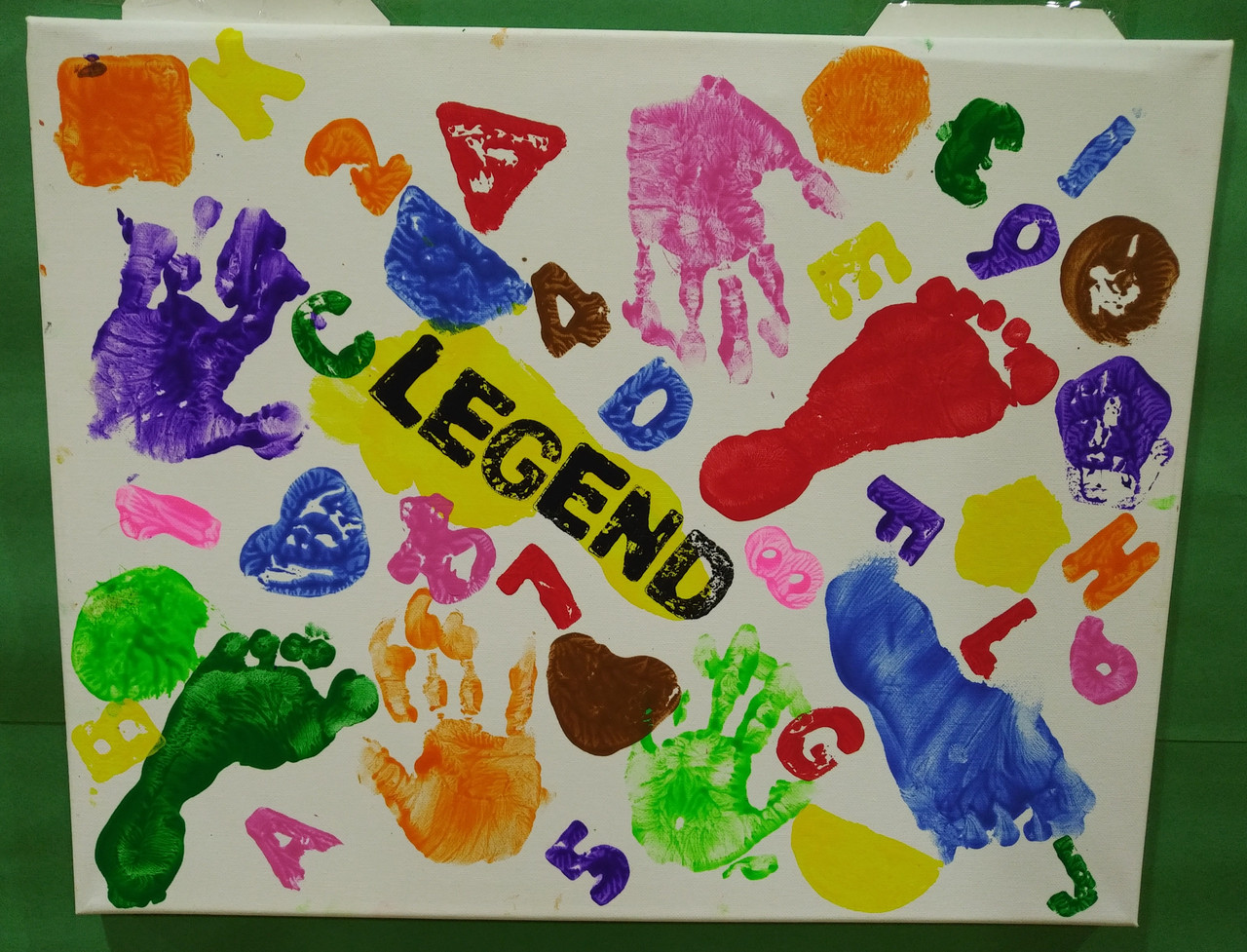 A colorful painting with hand prints and foot prints and letters surrounding the word "legend"