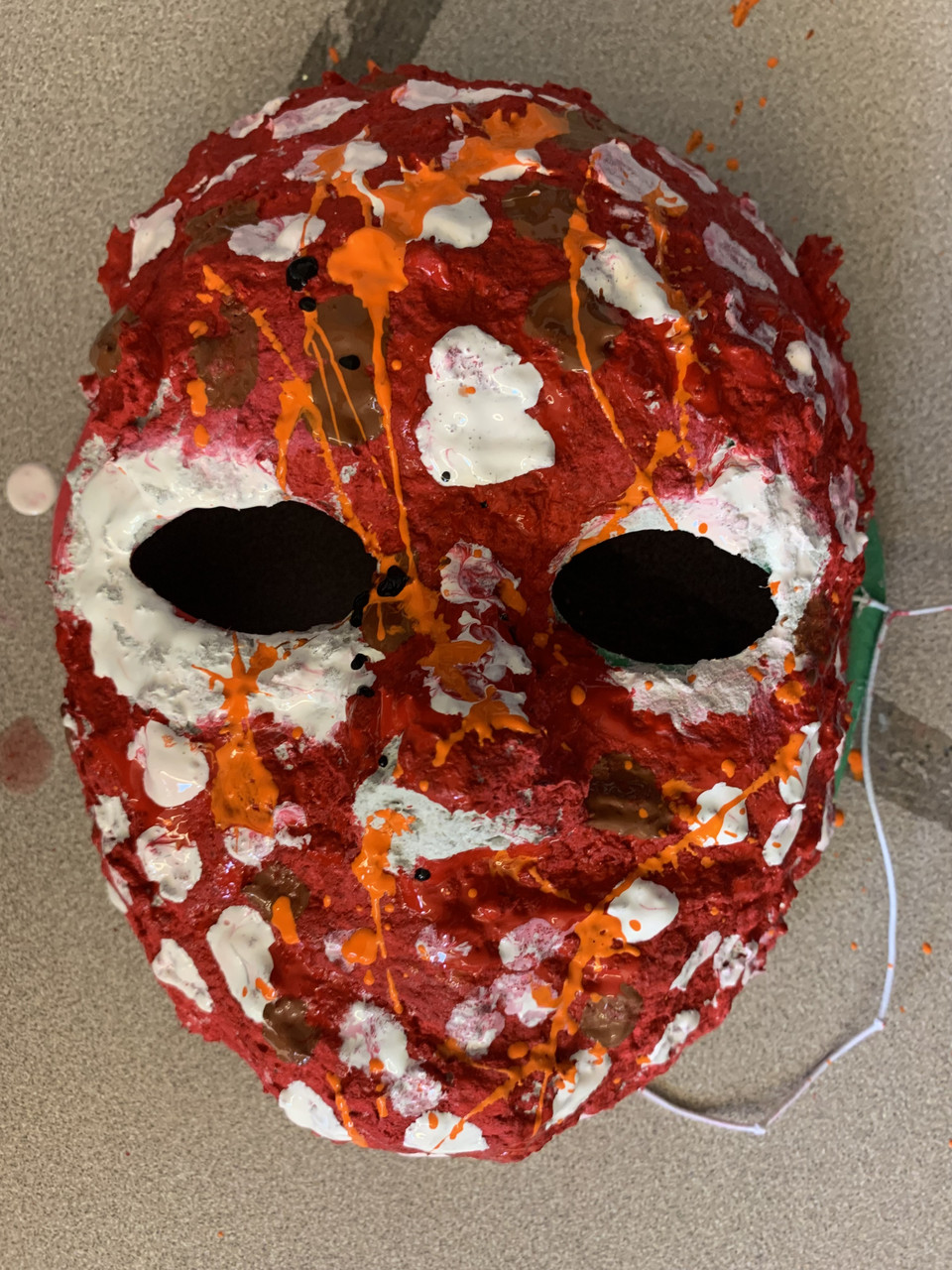 colorful mask with red strands of webbing across it