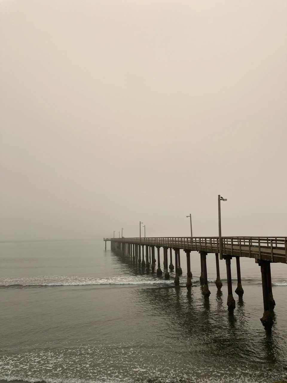 photo of pier stretching out into foggy ocean