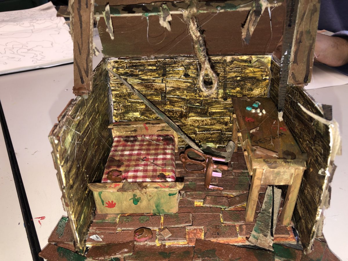 Miniature sculpture with a bed and desk made with earth tones and a variety of texture.