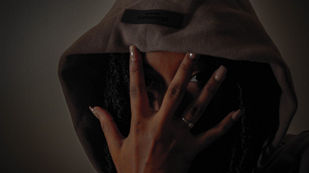 Photograph of woman with webbed hands and acrylic nails covering her face.