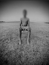 Blurred out boy sitting on a field in a lens