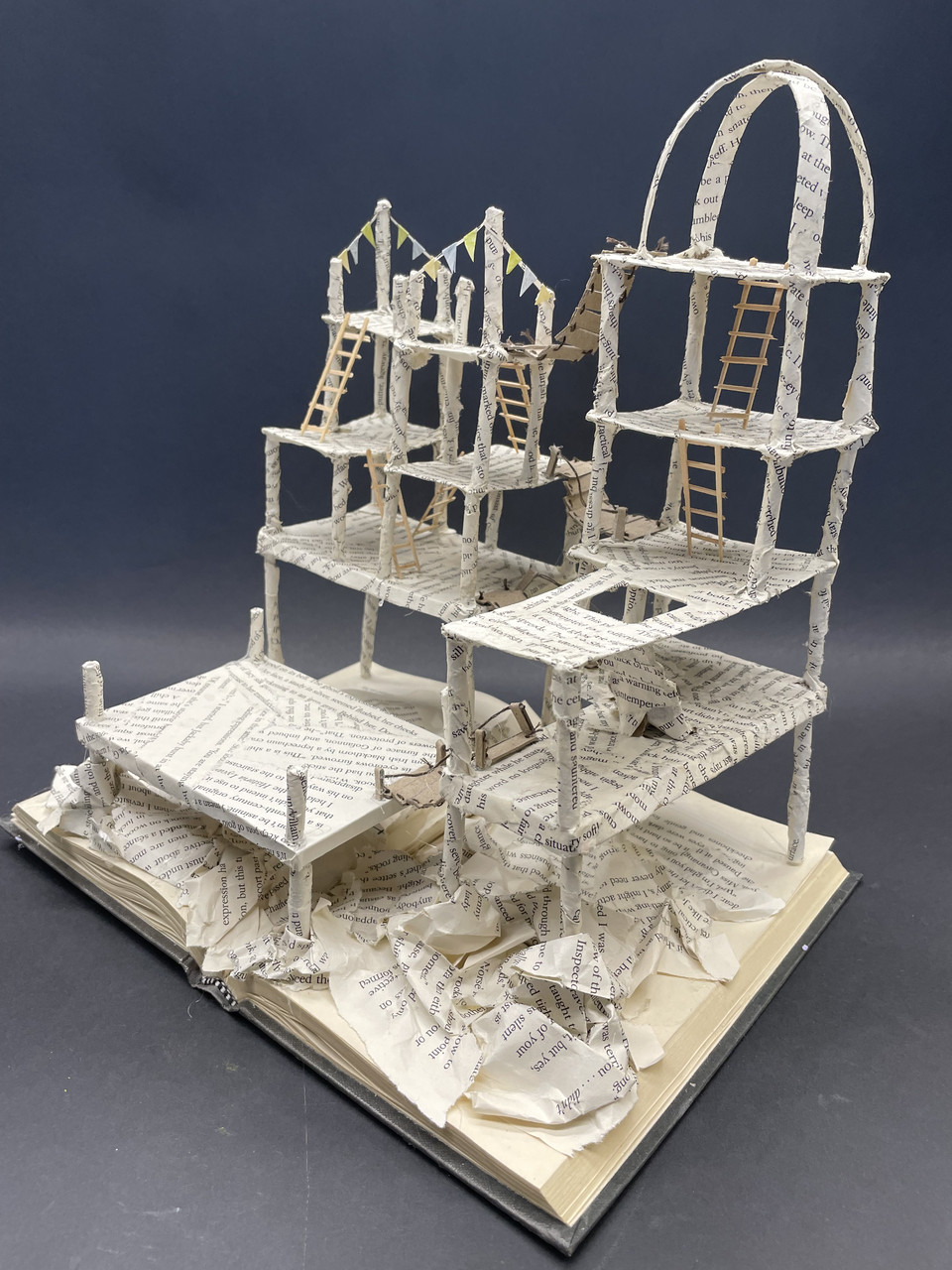 sculpture of a structure with ladders and platforms made from pages of text