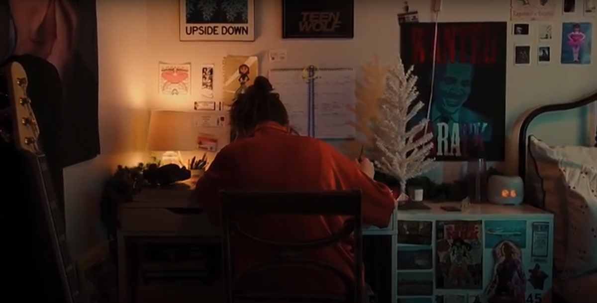 Person sitting in a cozy room writing at a desk