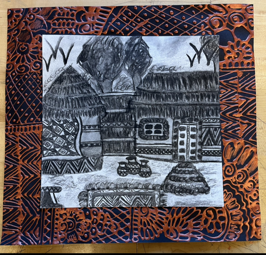 landscape of huts from a place in Pakistan framed with a blue and orange decorative border
