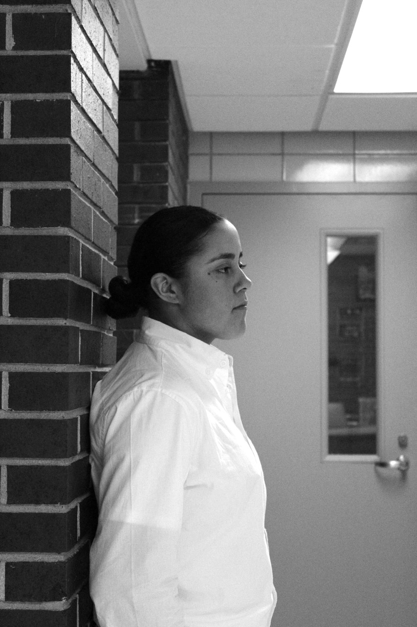 Black and white photo of a woman leaning against a wall.
