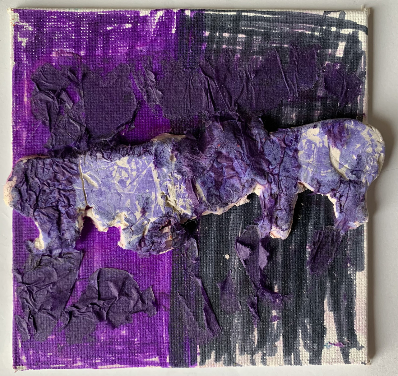Clay rhino and clay elephant ram heads together on top of a canvas. Both animals are covered in the color purple.