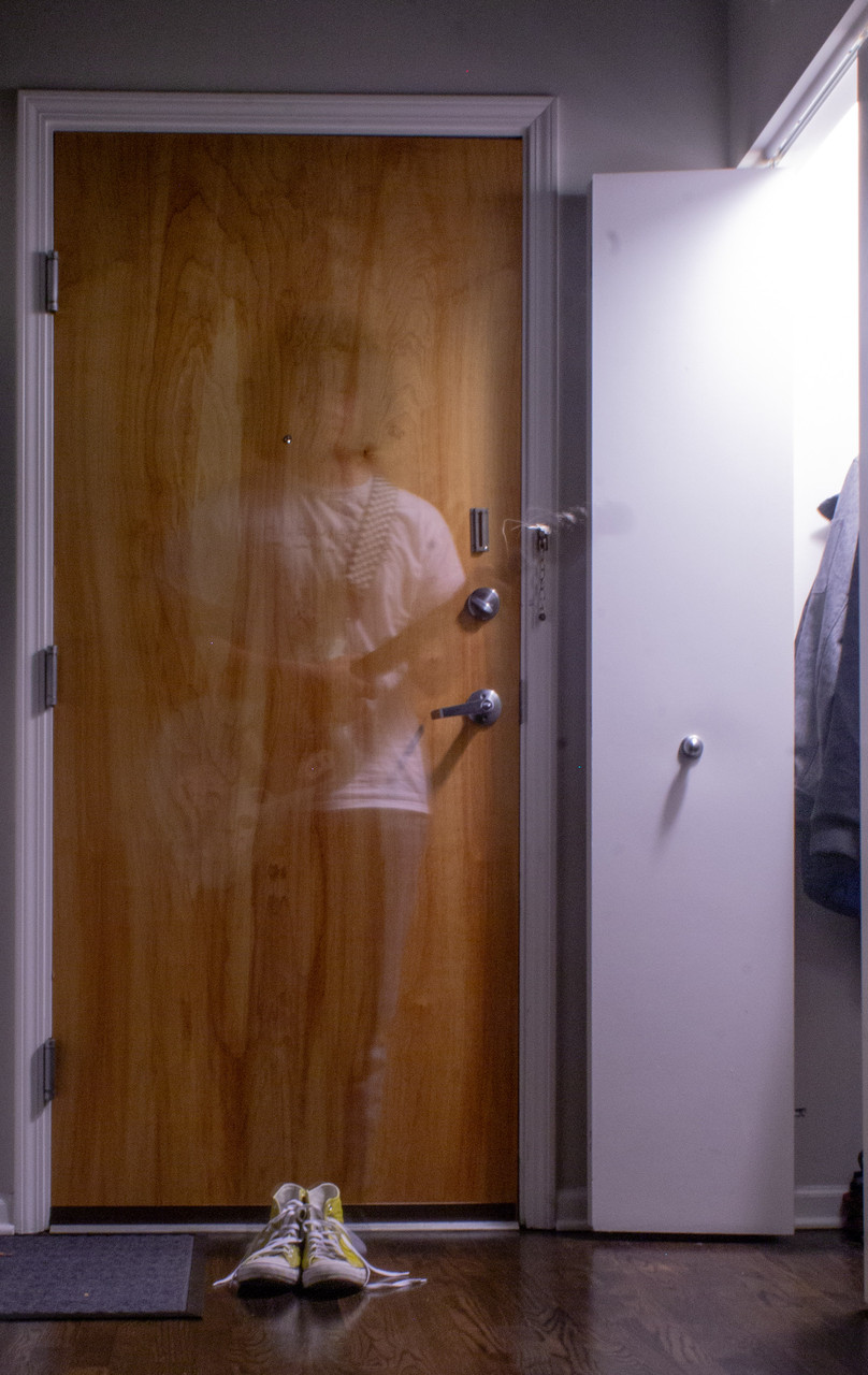 Photo of a ghost like figure in front of a door.