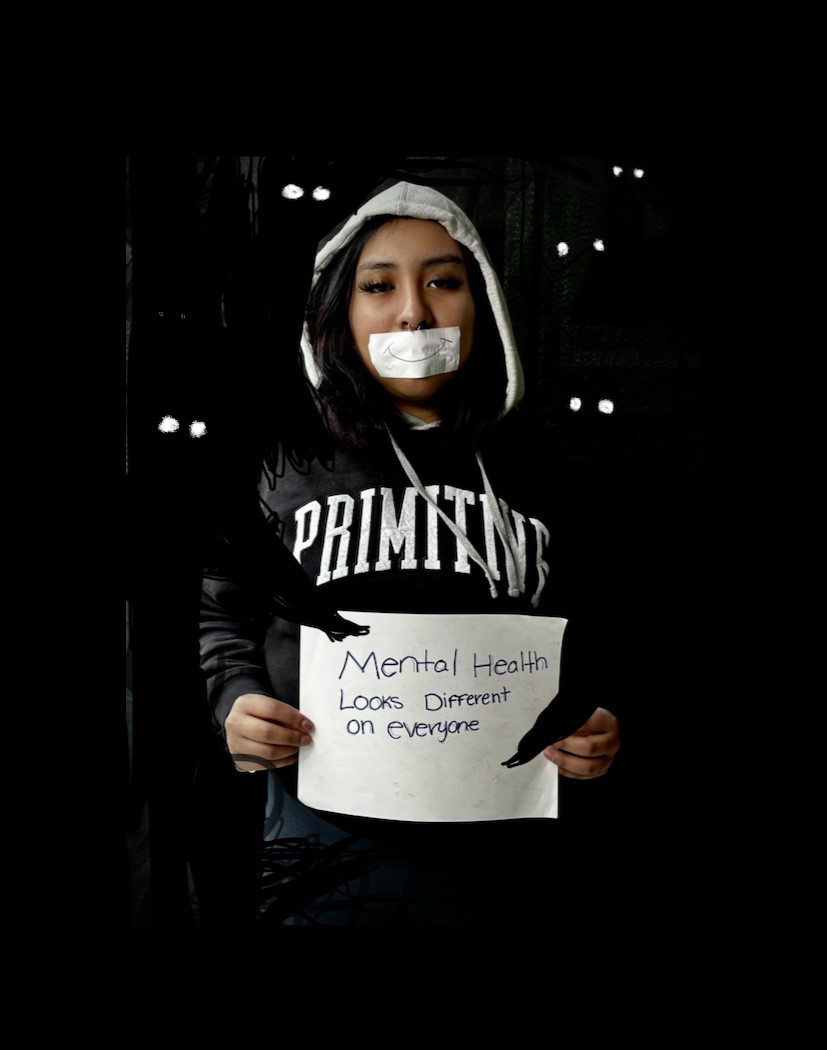 Person holding a paper sign with tape over mouth.