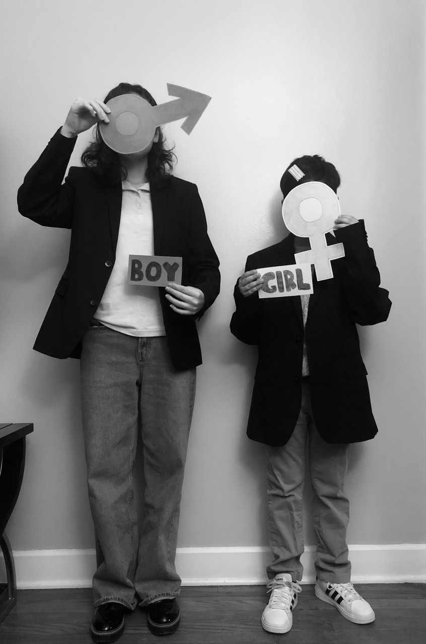 Black and white photo of two subjects holding signs over faces.