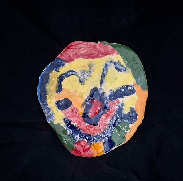 Ceramic smiling face painted with various colors.
