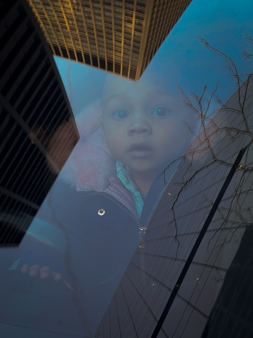 Photo of a baby's reflection on buildings.