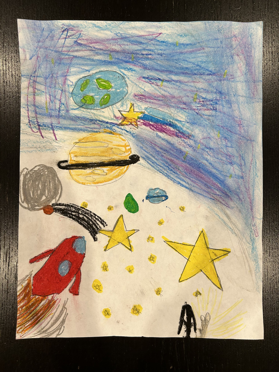 Drawing of a rocket flying through planets and stars in outer space.
