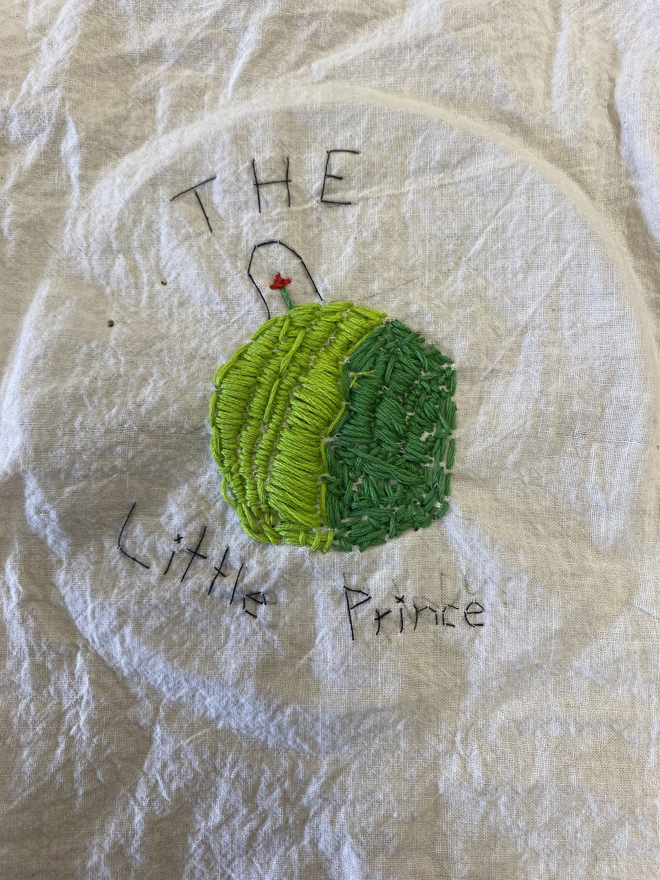 embroidered green circle with "the little prince" embroidered.