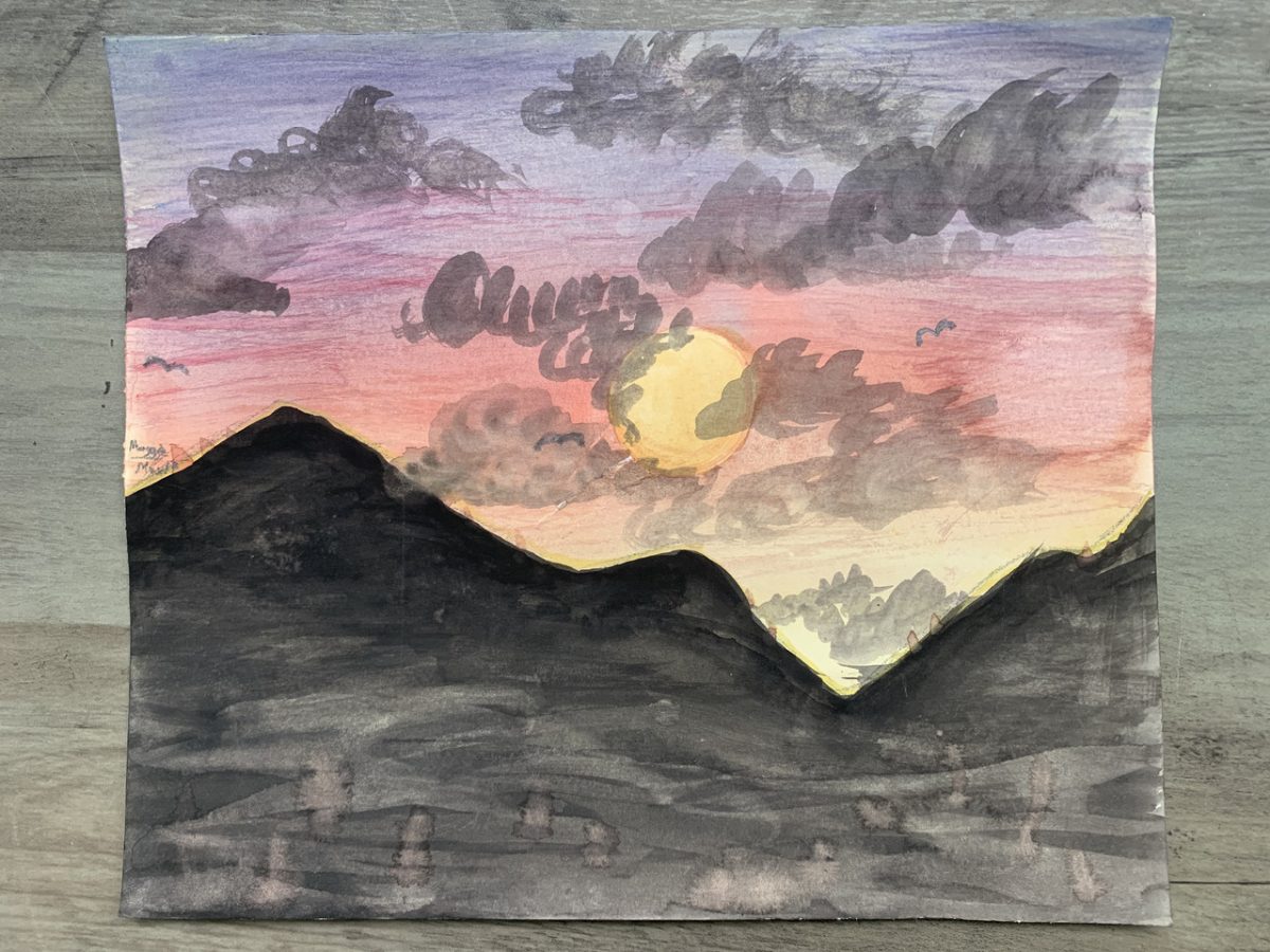 A yellow sunrise sits in colors of purple, pink, and yellow sky. It is covered with gray clouds and sits behind gray and black mountains.