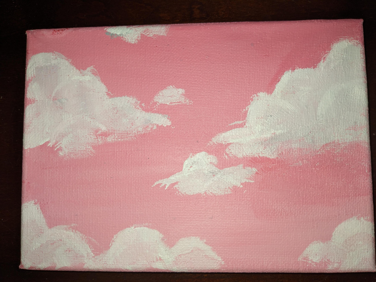 Painting of a pink sky with white, fluffy clouds.