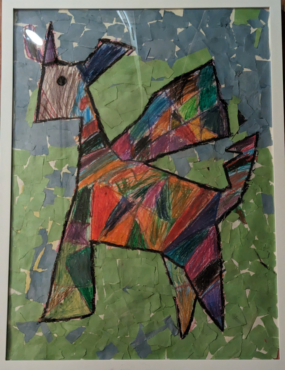 Collage of rainbow colors makes a unicorn. On the rest of the page, pieces of blue and green construction paper are layered.