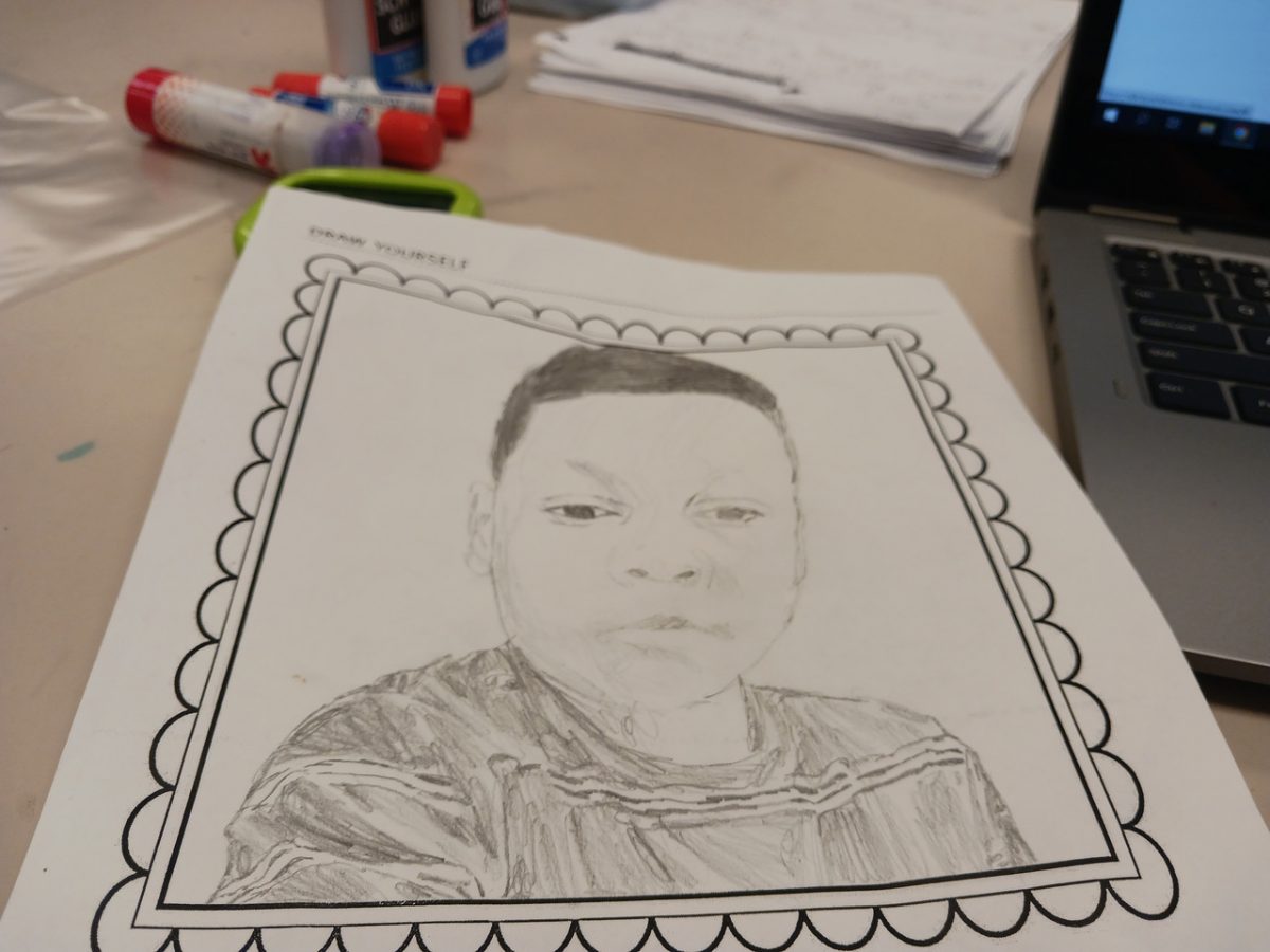 Self portrait a boy with a neutral facial expression on white paper.