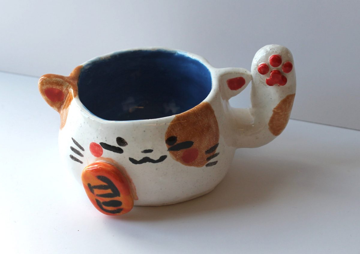 A ceramic mug with a face like a cat.