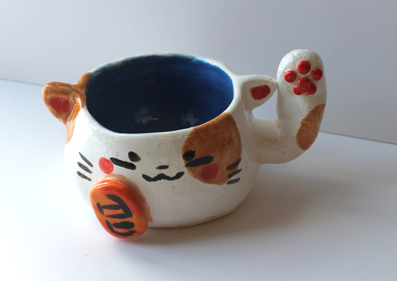 A ceramic mug with a face like a cat.