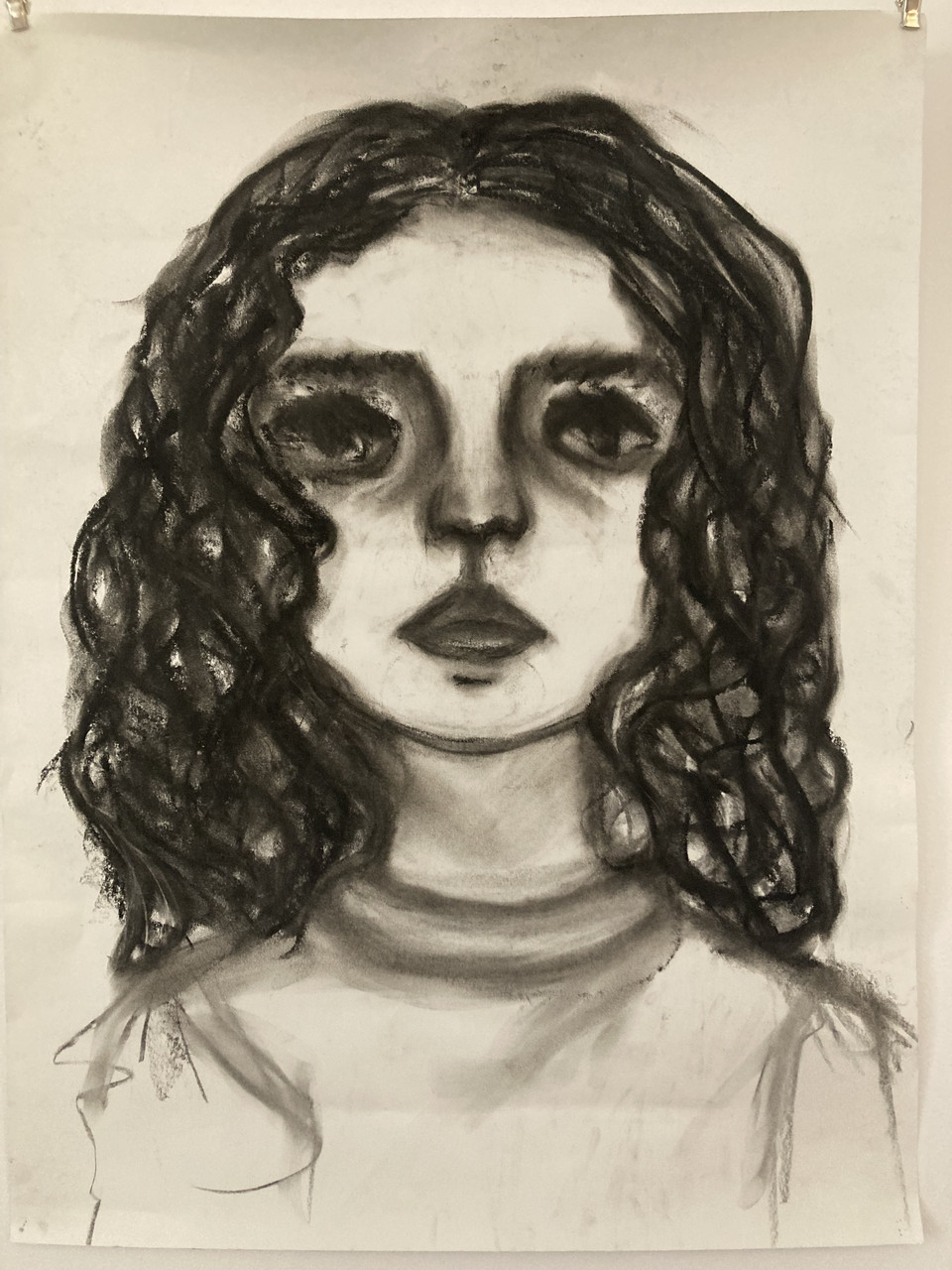 A charcoal drawing a girl with curly hair. She is facing the viewer.