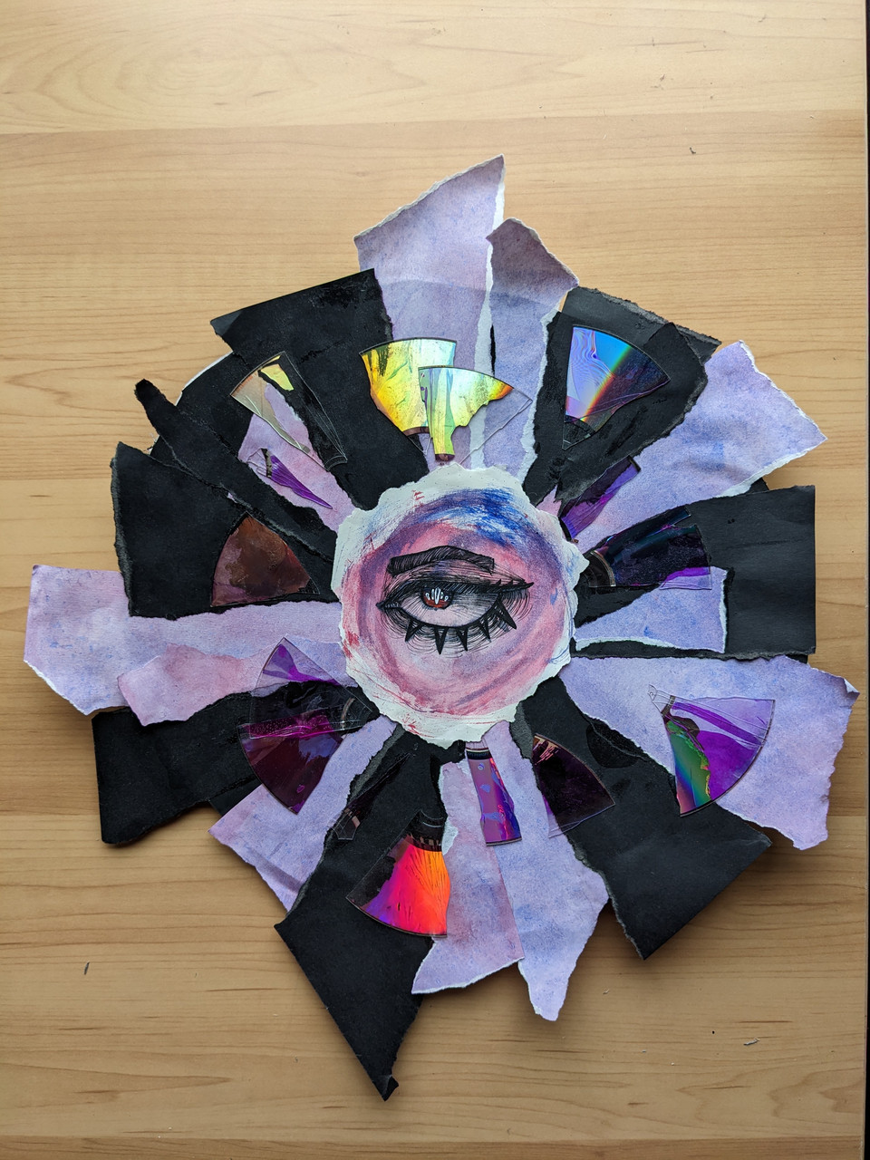 A painting of an eye is surrounded by purple and black purple triangle whose tip is attached to the circular eye painting.