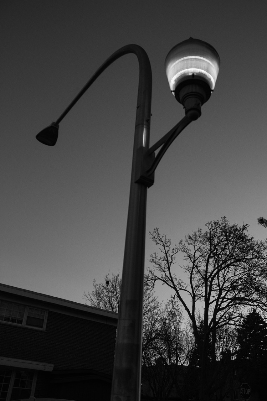 A black and white photo of a city light post.
