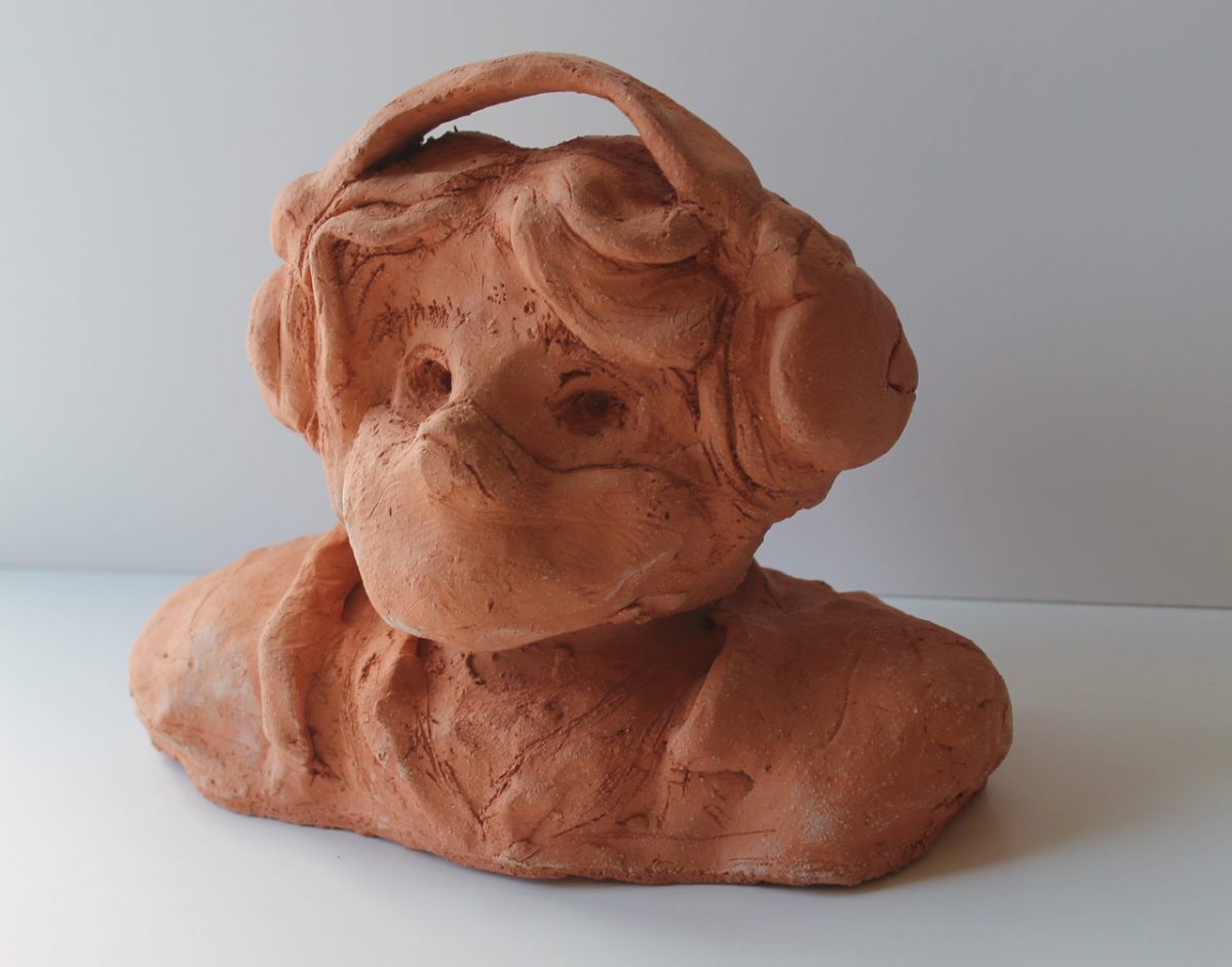 A bust of a student with headphones and a mask on.