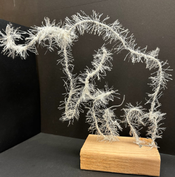The 3D outline of a horse is made of white thread. It is lofted on a wood block.