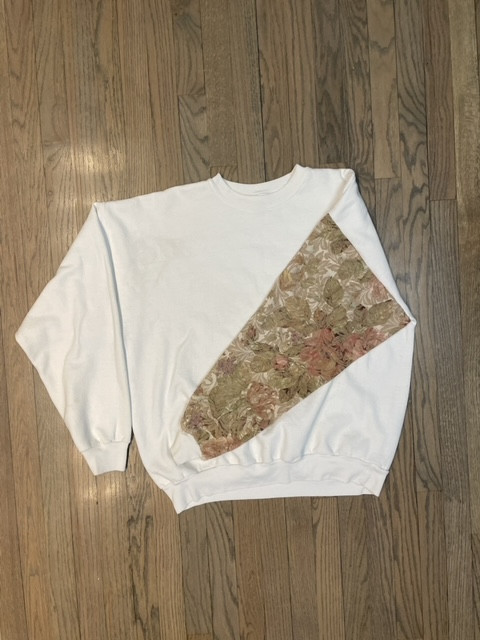 A white crewneck with a tan floral patterned sleeve.