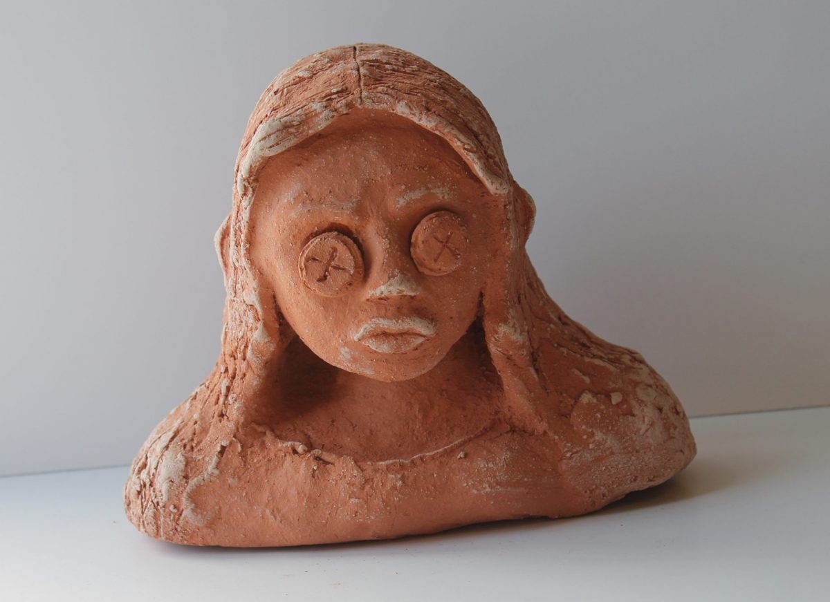 A bust of a girl with long hair and buttons for eyes.