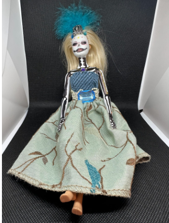 Barbie is colored in like a skeleton and wears a blue and grey dress.