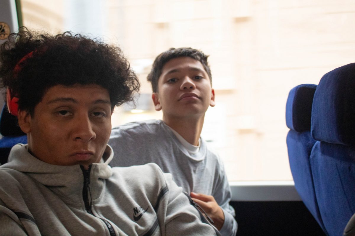 Photograph of two boys on a moving bus looking at the camera
