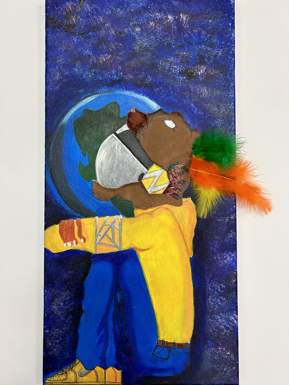Person with a yellow shirt and blue jeans in front of the planet Earth with a feather sticking out of its head.