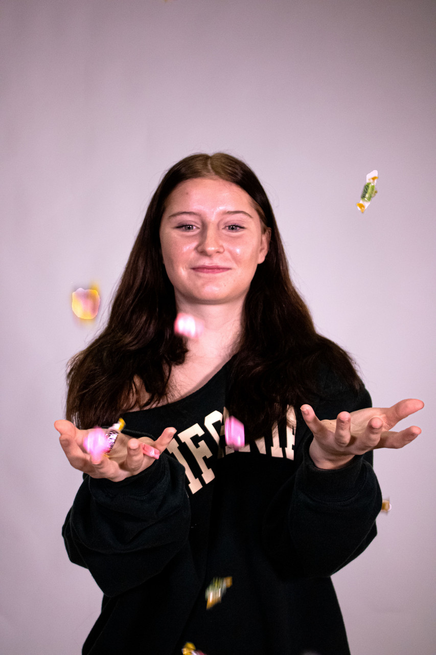 Photograph of a girl standing and catching falling candy