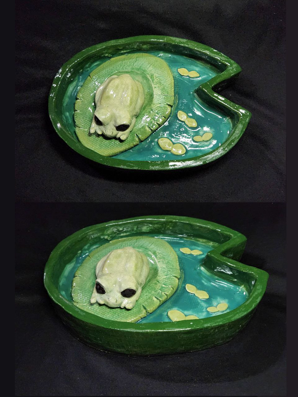 A sculpture of a frog resting on a lily-pad, within a lily-pad shaped pond.