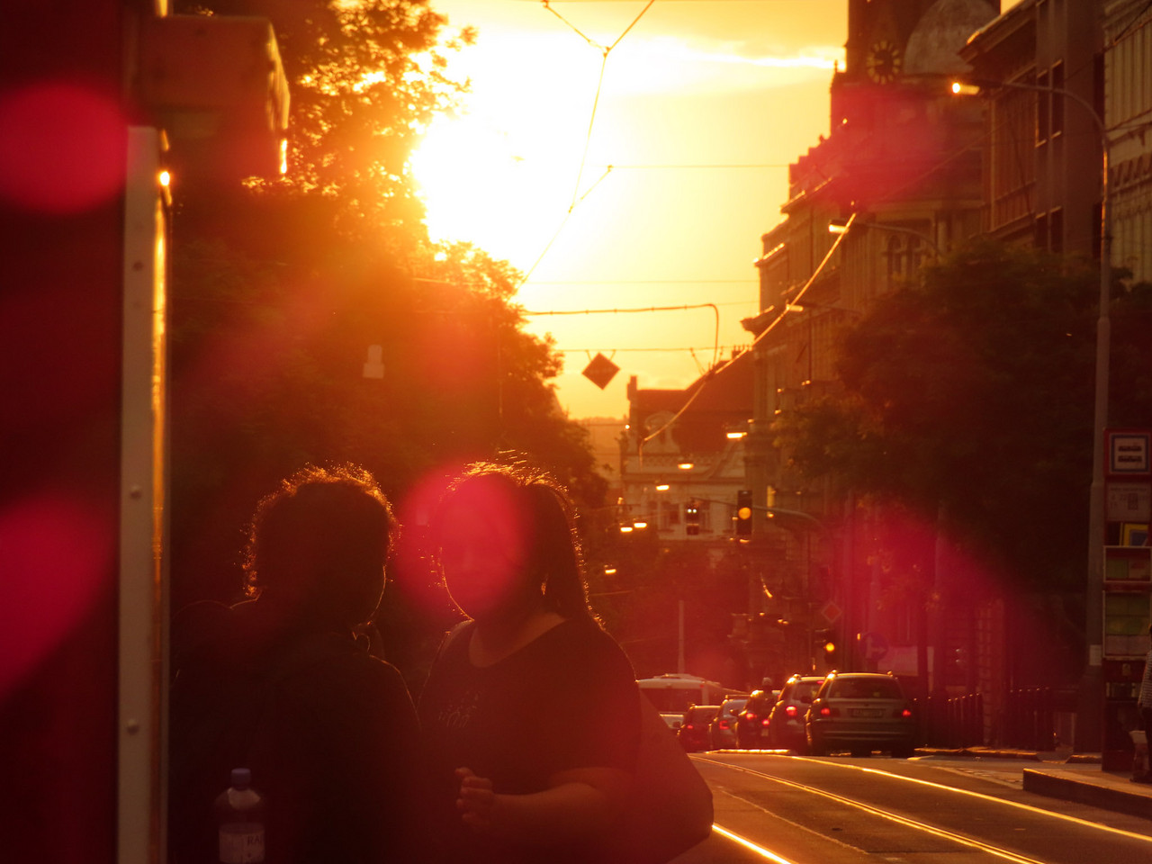 Sun drenched photo of a city street and two people talking